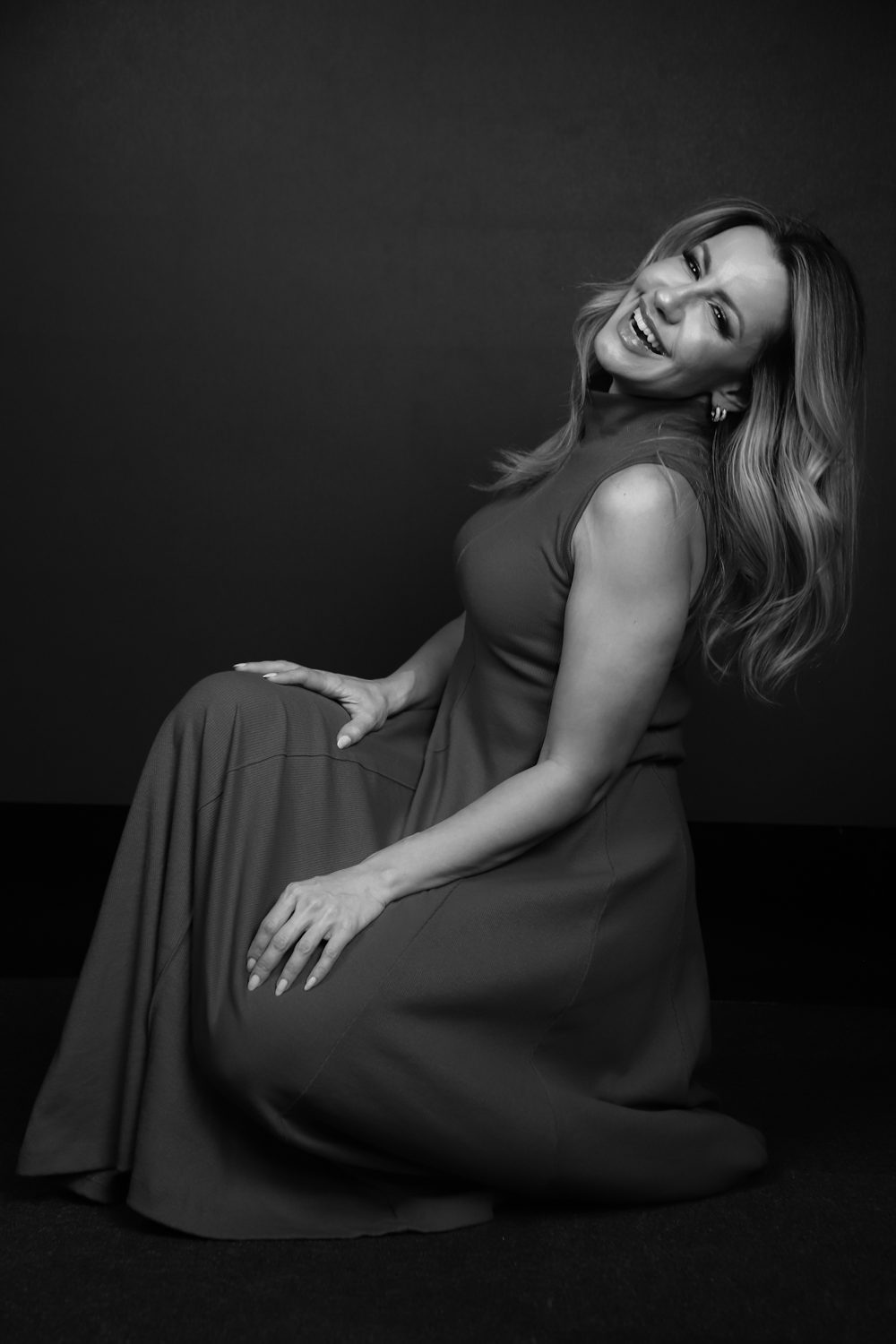 Ana Mascarenhas sentada, rindo, retrato de estúdio em preto e branco